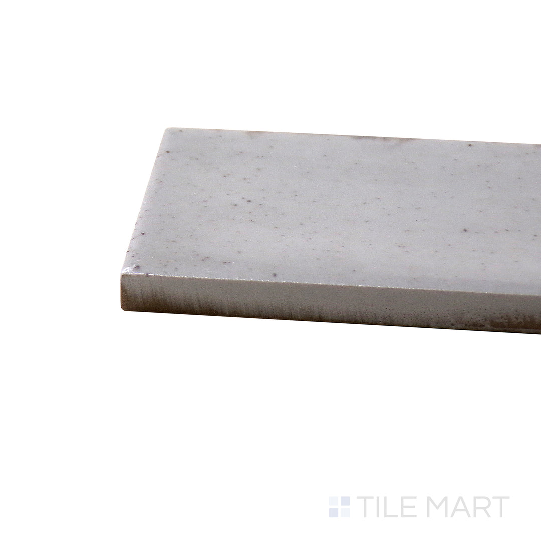 Angled view of Calpe Greige 2X6 Glossy Porcelain Tile, highlighting its soft greige tones with a polished, reflective surface.