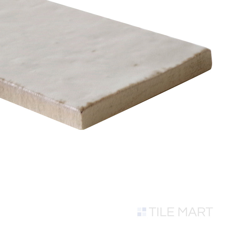 Diagonal view of Glace Mastice 3x8 glossy porcelain tile, showcasing its soft gray hues, smooth glossy surface, and elegant rectangular shape.  