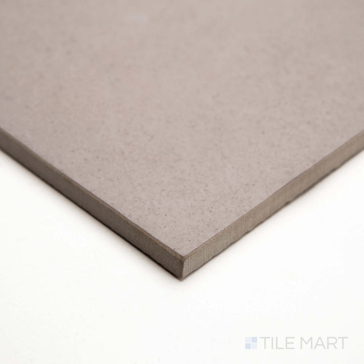 Displayed at an angle, Ash Beige 12x24 matte tile features subtle stone texture in a warm neutral hue.