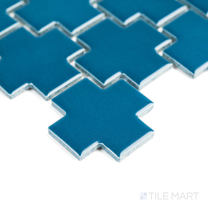 A glimpse from the edge shows Blue Cross matte mosaic tile, bold in shape and vibrant with a deep blue tone.