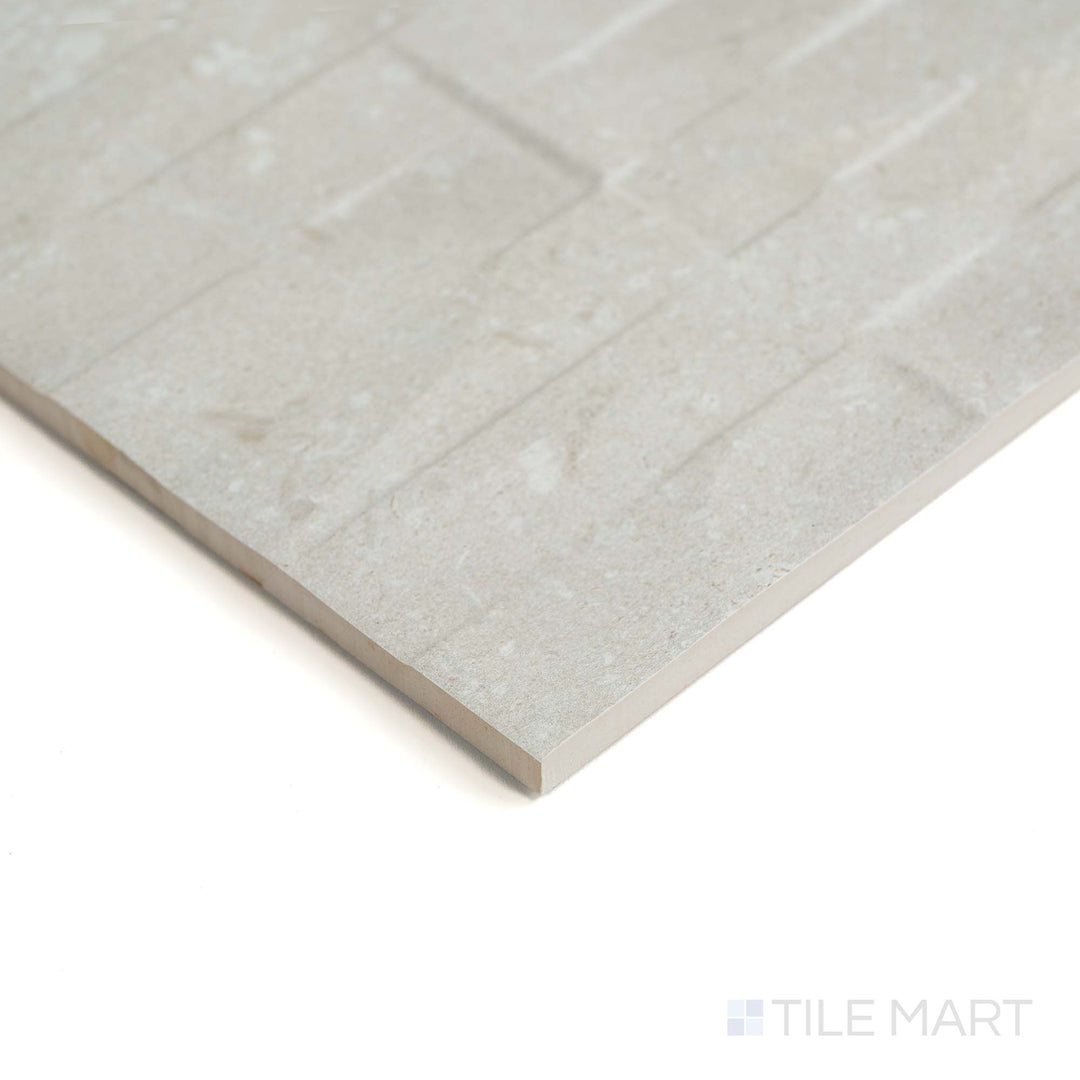 This corner perspective emphasizes the decorative texture of Pietra Coral Sand Deco 12X36 in a soft matte finish.