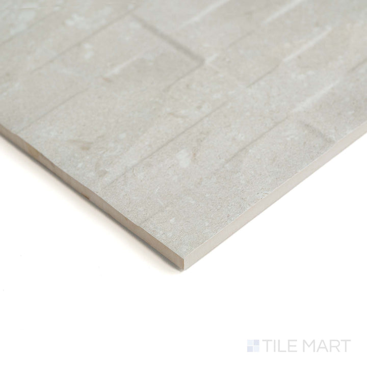 This corner perspective emphasizes the decorative texture of Pietra Coral Sand Deco 12X36 in a soft matte finish.