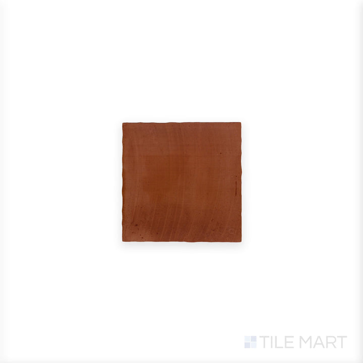 A complete Fuego Teja 9x9 matte porcelain tile is seen from a top-down angle, revealing its warm clay hue and subtle matte surface detail.