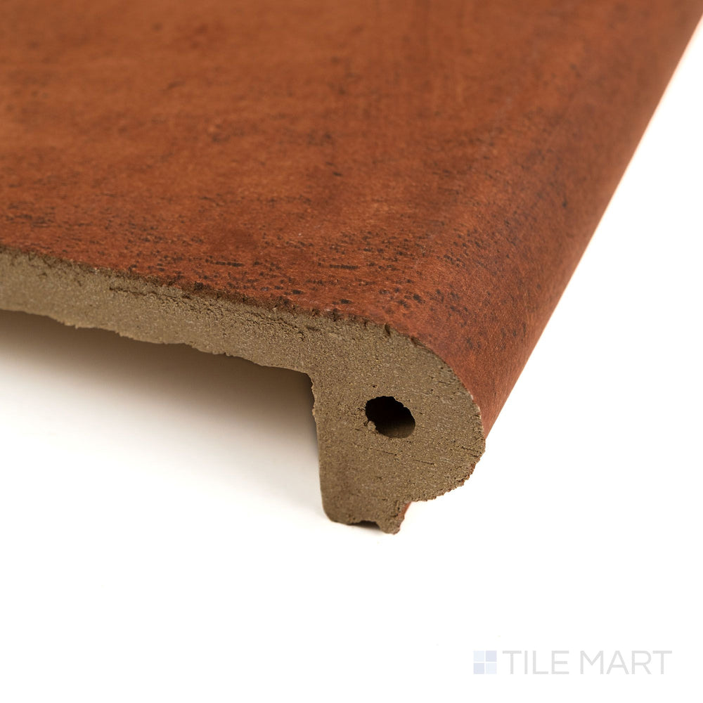 Photographed from an angle, the Fuego Teja Stair Coping 13x18 matte porcelain tile reveals its terracotta tone, textured surface, and curved coping edge.