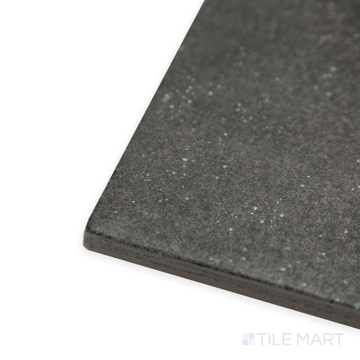 Angled close-up of Stage Charcoal 4x4 matte porcelain tile, emphasizing its deep charcoal shade, matte finish, and sharp corner transition.