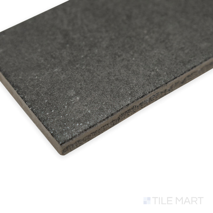 Side-angle shot of Stage Charcoal 2.5x12 matte porcelain tile, emphasizing its deep grey-black tone, straight-cut edges, and fine matte texture.