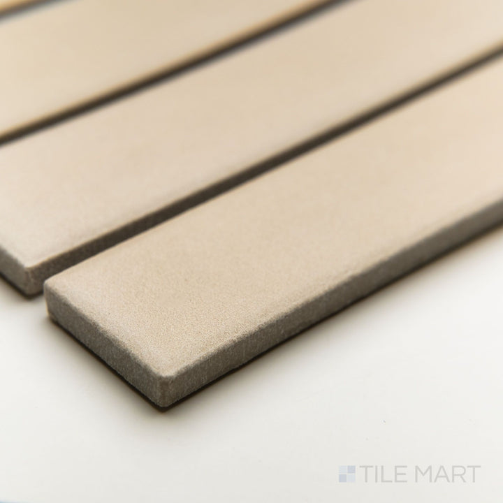 Corner shot of Amuri Avorio 1x6 mosaic tiles arranged in a vertical grid with creamy tones and a matte surface.