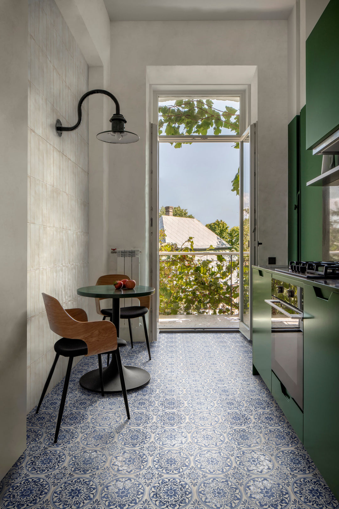 Modern kitchen featuring green cabinetry, patterned flooring, and a balcony-access door, with Amuri Brick Avorio 2x12 Matte Porcelain Tile adding a soft, textured backdrop.
