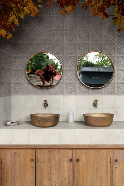 Bathroom with two round mirrors, brass sinks, and wooden cabinets, styled with Amuri Struttura 3D Gelosia Grigio 8x8 Matte Porcelain Tile to add dimension and sophistication.