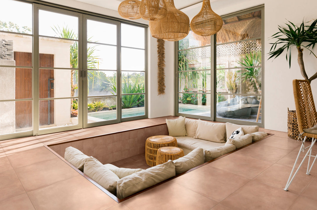 Modern living space with a sofa, coffee table, and large windows, designed with Amuri Cotto 24x24 Matte Porcelain Tile for a rich, terracotta-toned base.