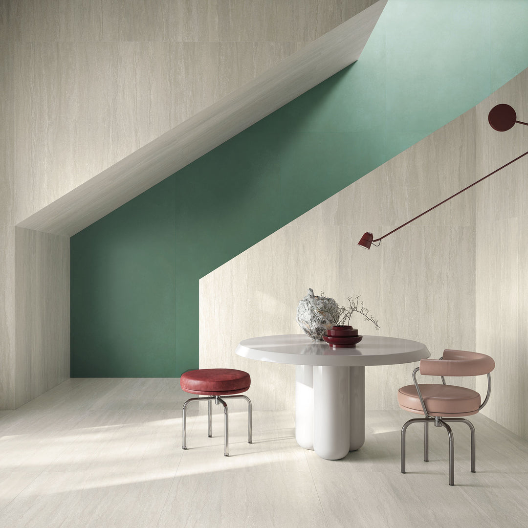 Modern dining area with a white marble table and pink stools framed by green and beige walls, featuring Dorset Vein Cut Bianco 24x48 Matte Porcelain Tile for a spacious, elegant effect.