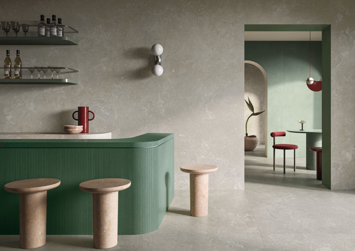 Modern interior with a green bathtub, wooden stools, and a mirror reflecting the space, enriched by Dorset Cross Cut Cenere 48x48 Matte Porcelain Tile in soft gray shades.