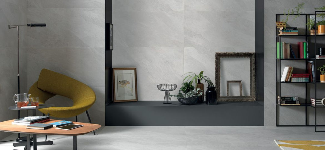 Modern interior with a yellow chair, coffee table, and bookshelf, enhanced by Hurricane White 24x48 Matte Porcelain Tile for a clean and spacious look.