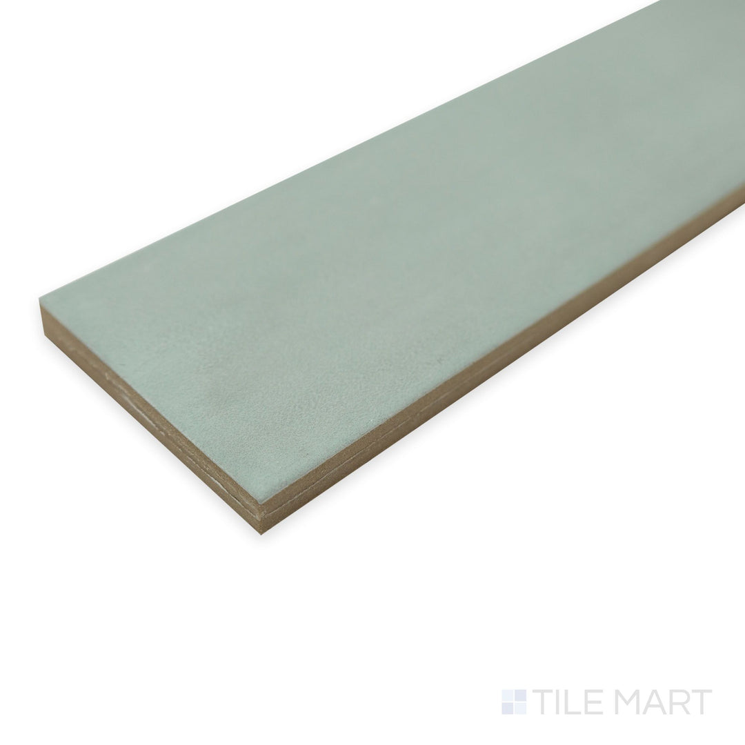Corner angle of Passaggi Green 2x9 porcelain tile with a soft botanical hue and matte texture.
