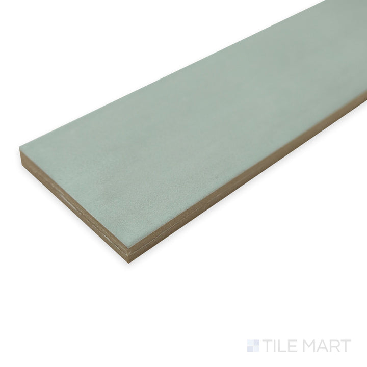 Corner angle of Passaggi Green 2x9 porcelain tile with a soft botanical hue and matte texture.