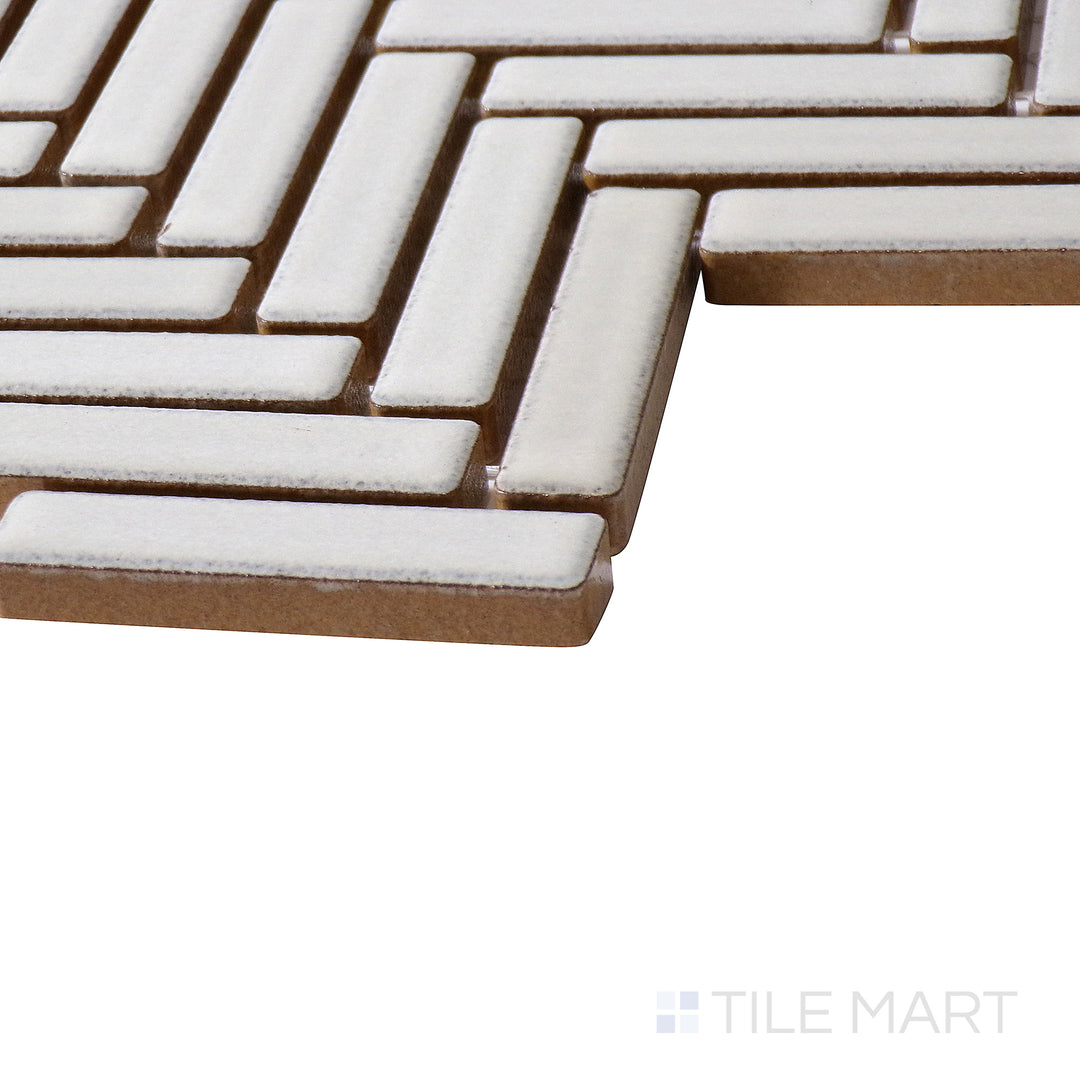 Corner-focused image of 90° Putty Herringbone gloss glazed porcelain mosaic, emphasizing its warm taupe hue, reflective finish, and the way its precise cuts meet at the edge.