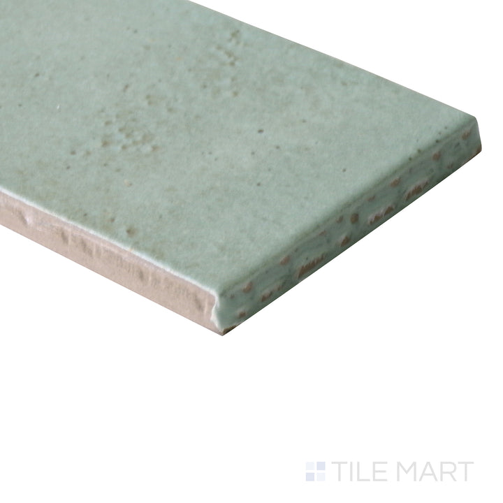 Angled view of Celine Sage 2x6 matte glazed porcelain tile, emphasizing its soft green undertone, crisp edges, and the smooth matte surface forming a flawless transition.
