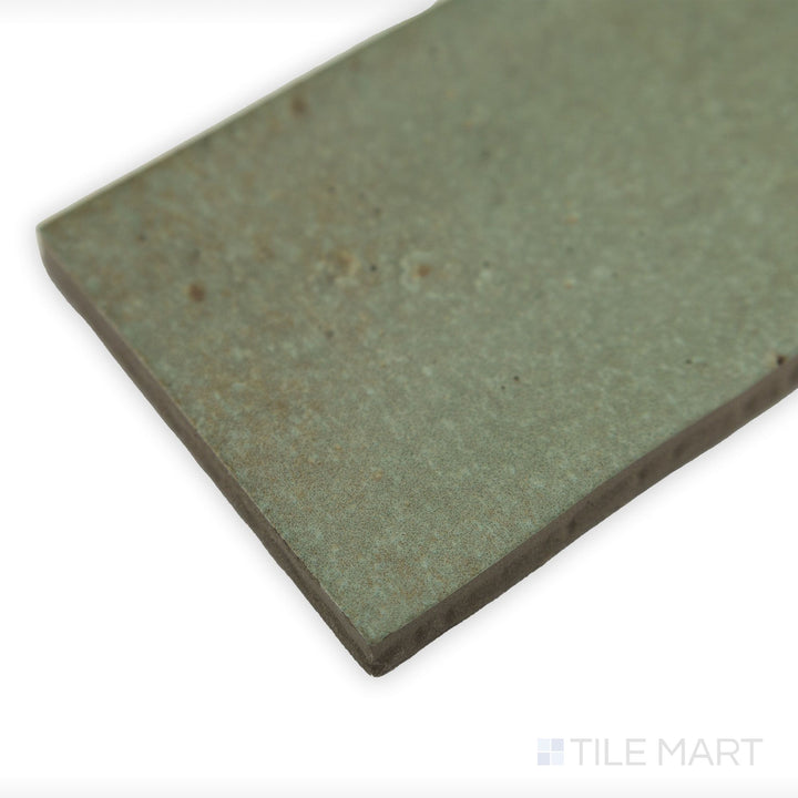 Corner-focused image of Celine Sage 2.5x12 matte glazed porcelain tile, drawing attention to its muted green tone, matte surface, and sharp corner details.