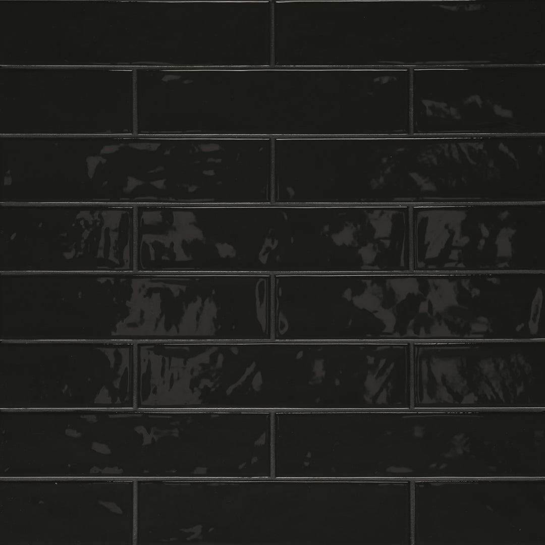 Captured from above, the Clara Noir 2.75X11 glossy porcelain tile showcases a deep black shade with a sleek, polished glaze that subtly mirrors light for a sophisticated look.