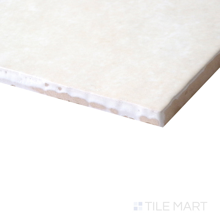 Corner-focused image of Cloe Crème 5x5 gloss glazed ceramic tile, showcasing its soft beige tone, high-gloss surface, and precisely cut edges creating a smooth intersection.