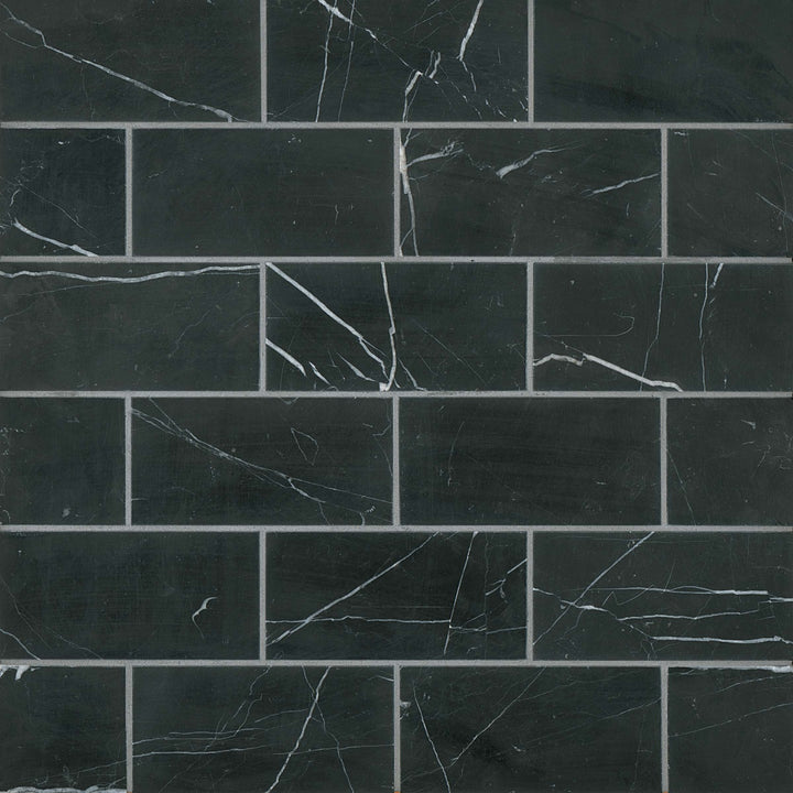 From a bird’s-eye perspective, the Ferrara Nero 3X6 honed marble tile showcases deep black hues with subtle white veining, enhancing any space with bold sophistication.