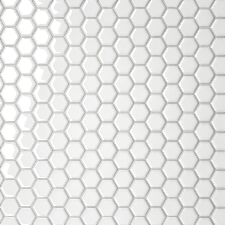 A top-down capture of the Le Café White 1" Hexagon Gloss Porcelain Mosaic presents a brilliant white surface with a reflective glaze, creating a luminous and timeless geometric pattern.