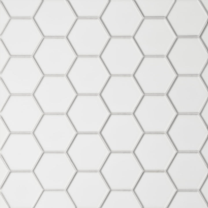 A top-down shot of the Le Café White 2" Hexagon Matte Porcelain Mosaic emphasizes its smooth, velvety matte texture in pristine white, offering a soft yet structured geometric appeal.