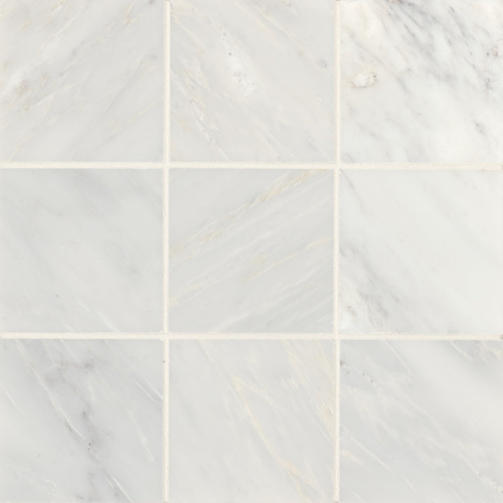 A top-down display of Monet Oriental White 4X4 Honed Marble presents its crisp white backdrop infused with elegant, muted veining for a clean, polished look.