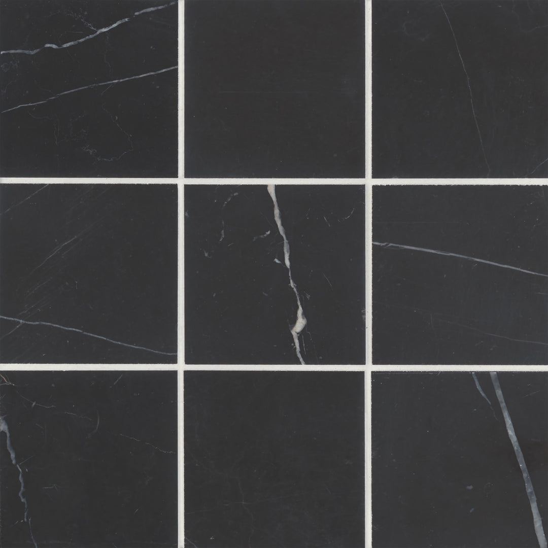 An overhead capture of Monet Nero Marquina 4X4 Honed Marble highlights its rich black surface, punctuated with striking white veining for an opulent, high-contrast look.