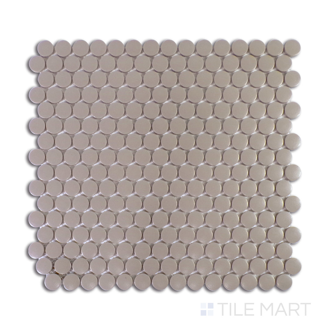 An intricate macro shot of Marin Coastal Cliff 3/4" Penny Round Matte Glazed Porcelain Mosaic captures its subtle coastal tones and non-reflective finish, perfect for serene aesthetics.