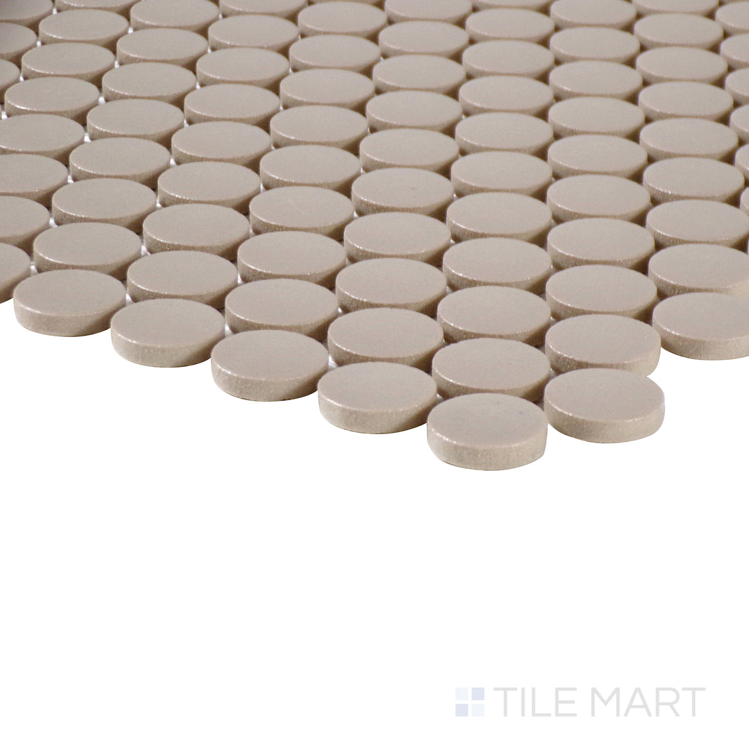 Side-angle close-up of Marin Coastal Cliff 3/4" penny round matte glazed porcelain mosaic, highlighting its warm neutral tone, smooth matte texture, and crisp intersection at the edges.