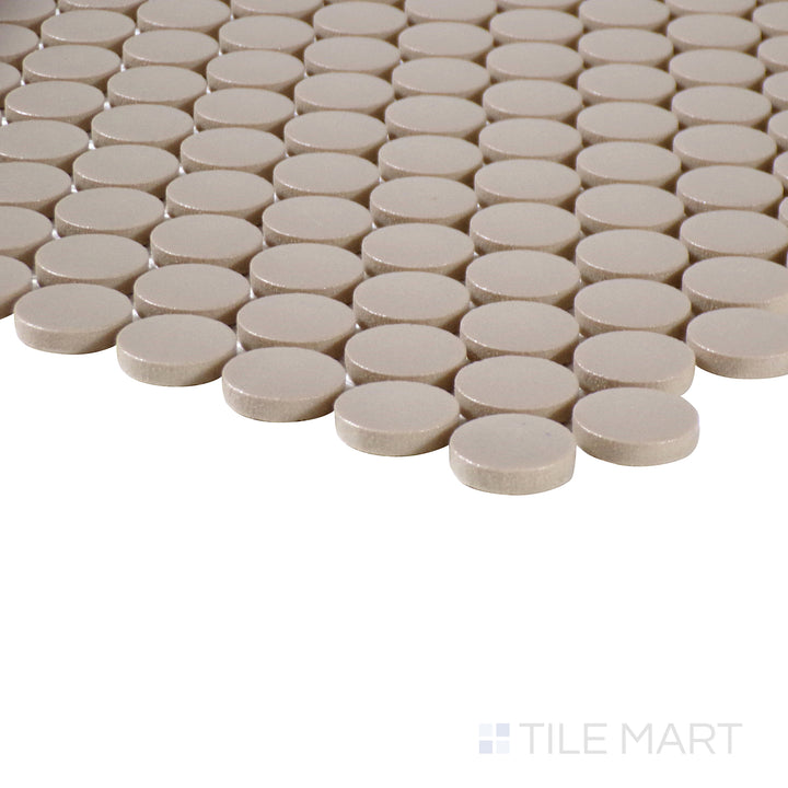 Side-angle close-up of Marin Coastal Cliff 3/4" penny round matte glazed porcelain mosaic, highlighting its warm neutral tone, smooth matte texture, and crisp intersection at the edges.