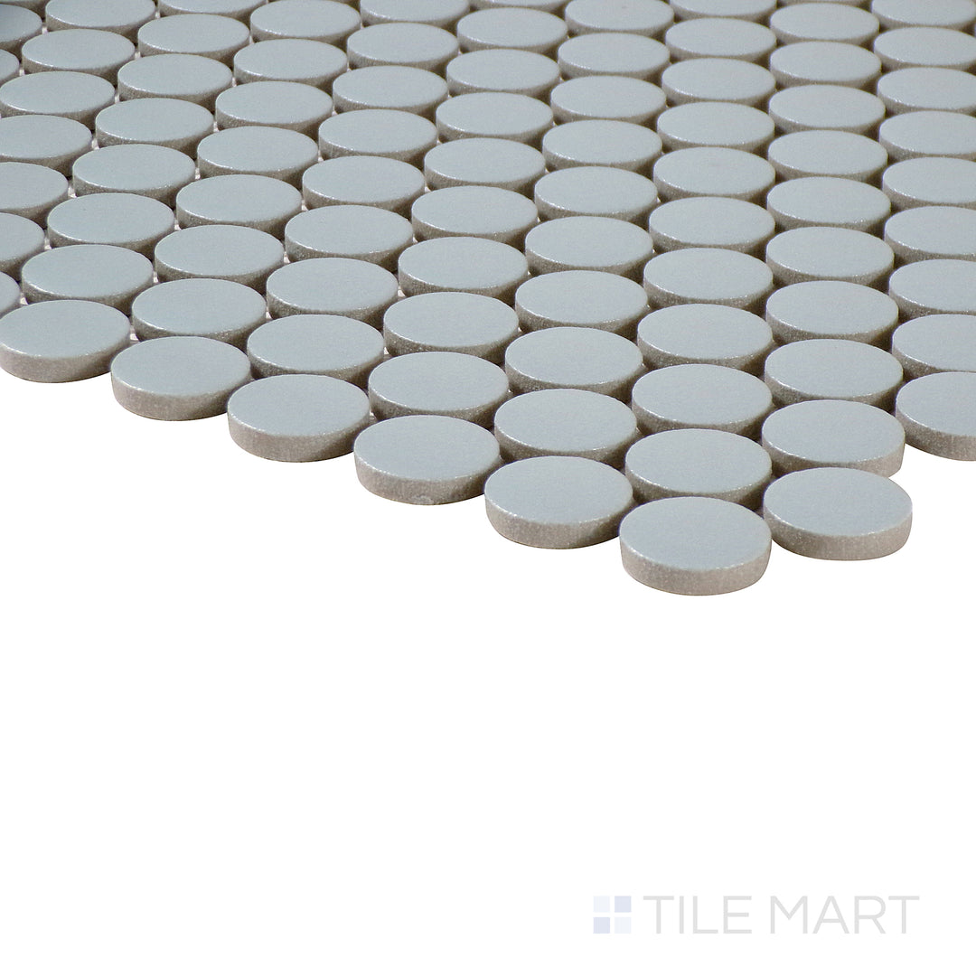 Angled close-up of Marin Misty Blue 3/4" penny round matte glazed porcelain mosaic, featuring its soft blue shade, structured penny layout, and sharp edge alignment.