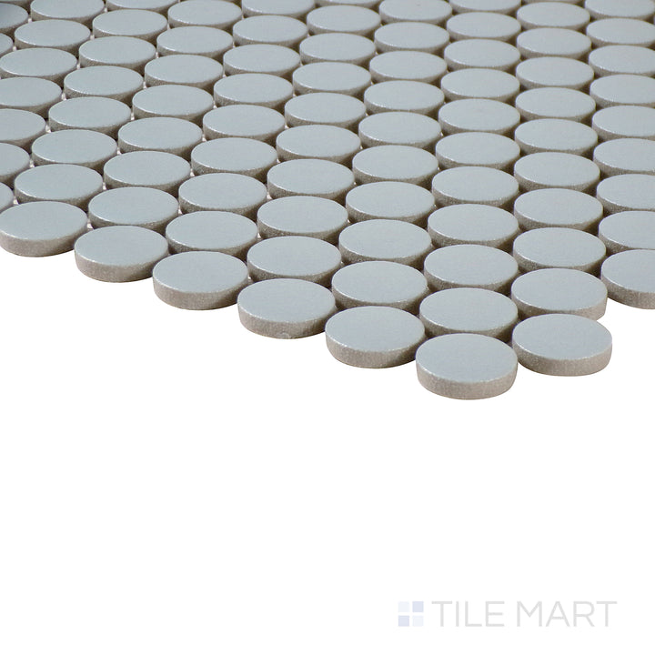 Angled close-up of Marin Misty Blue 3/4" penny round matte glazed porcelain mosaic, featuring its soft blue shade, structured penny layout, and sharp edge alignment.