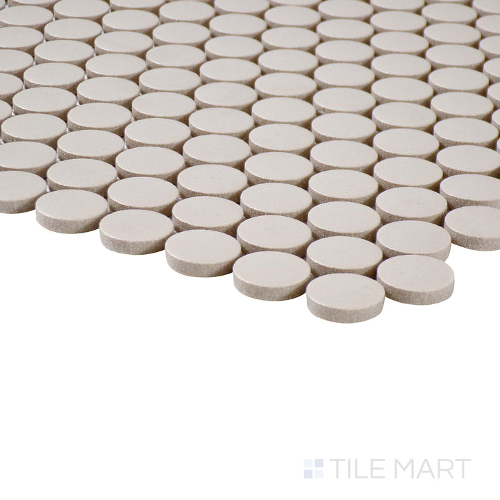 Corner-focused image of Marin Sand Dollar 3/4" penny round matte glazed porcelain mosaic, emphasizing its warm beige hue, even matte finish, and how the edges align at the corner.