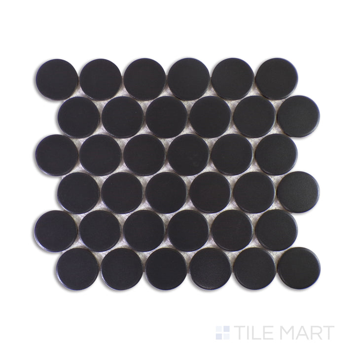 An elegant macro shot of Marin Black Sea 2" Penny Round Matte Glazed Porcelain Mosaic captures its deep ebony shade and velvety matte glaze, making a bold, modern statement.
