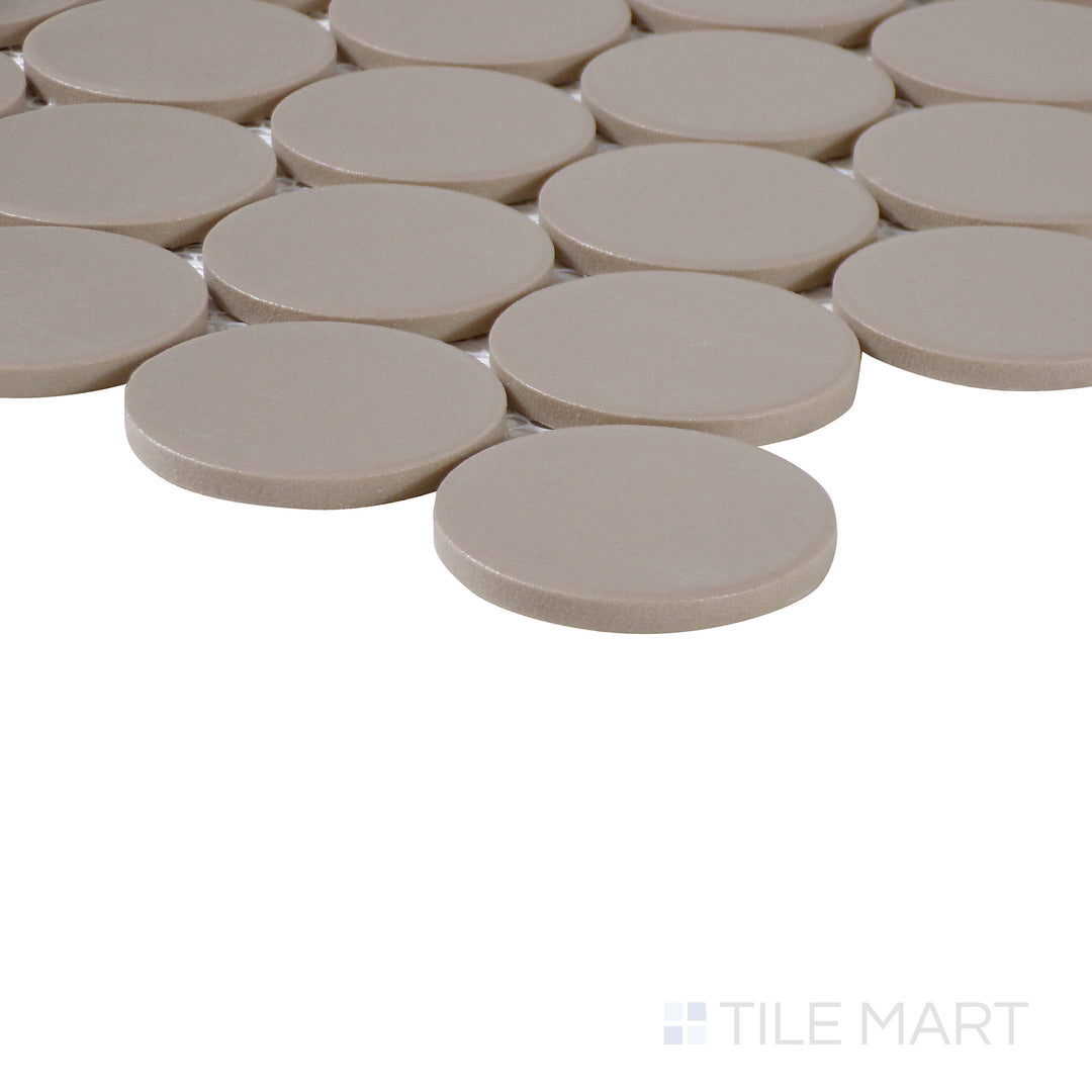 Side-angle close-up of Marin Coastal Cliff 2" penny round matte glazed porcelain mosaic, highlighting its neutral sandy beige hue, soft matte coating, and structured corner alignment.