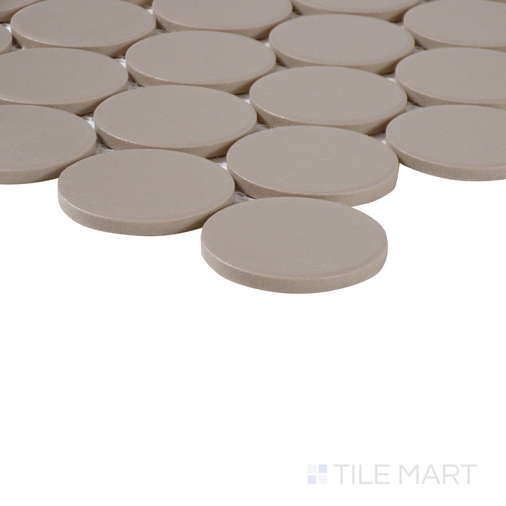 Side-angle close-up of Marin Coastal Cliff 2" penny round matte glazed porcelain mosaic, highlighting its neutral sandy beige hue, soft matte coating, and structured corner alignment.