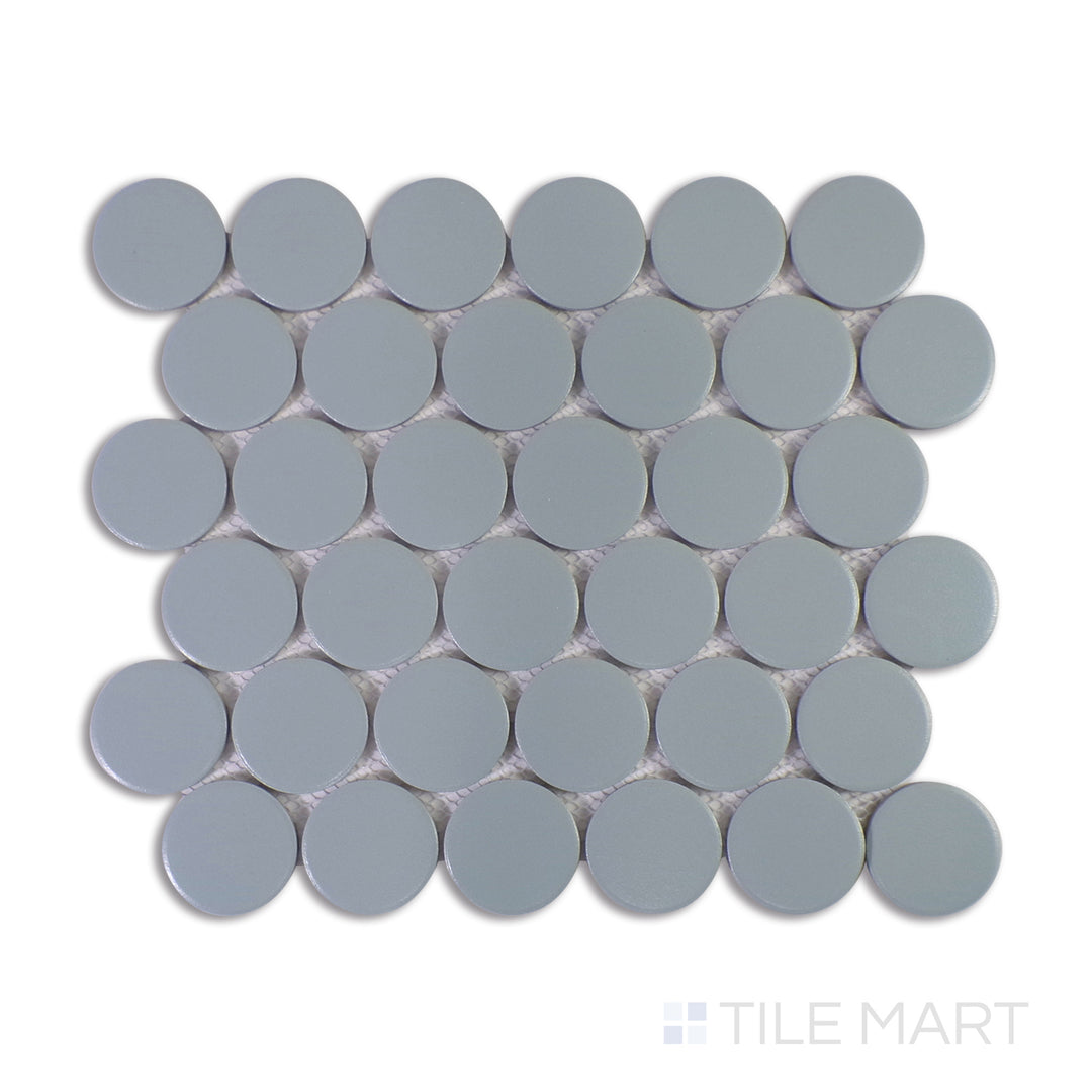 A close-up view of Marin Misty Blue 2" Penny Round Matte Glazed Porcelain Mosaic reveals its soft, misty blue tones with a smooth matte finish, adding a calming aesthetic.