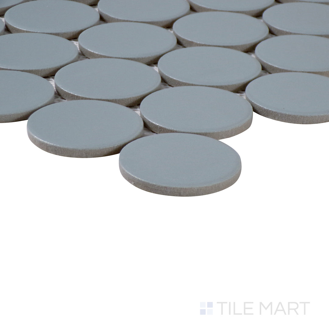 Angled close-up of Marin Misty Blue 2" penny round matte glazed porcelain mosaic, featuring its subtle blue hue, non-glossy texture, and the clean arrangement at the edges.