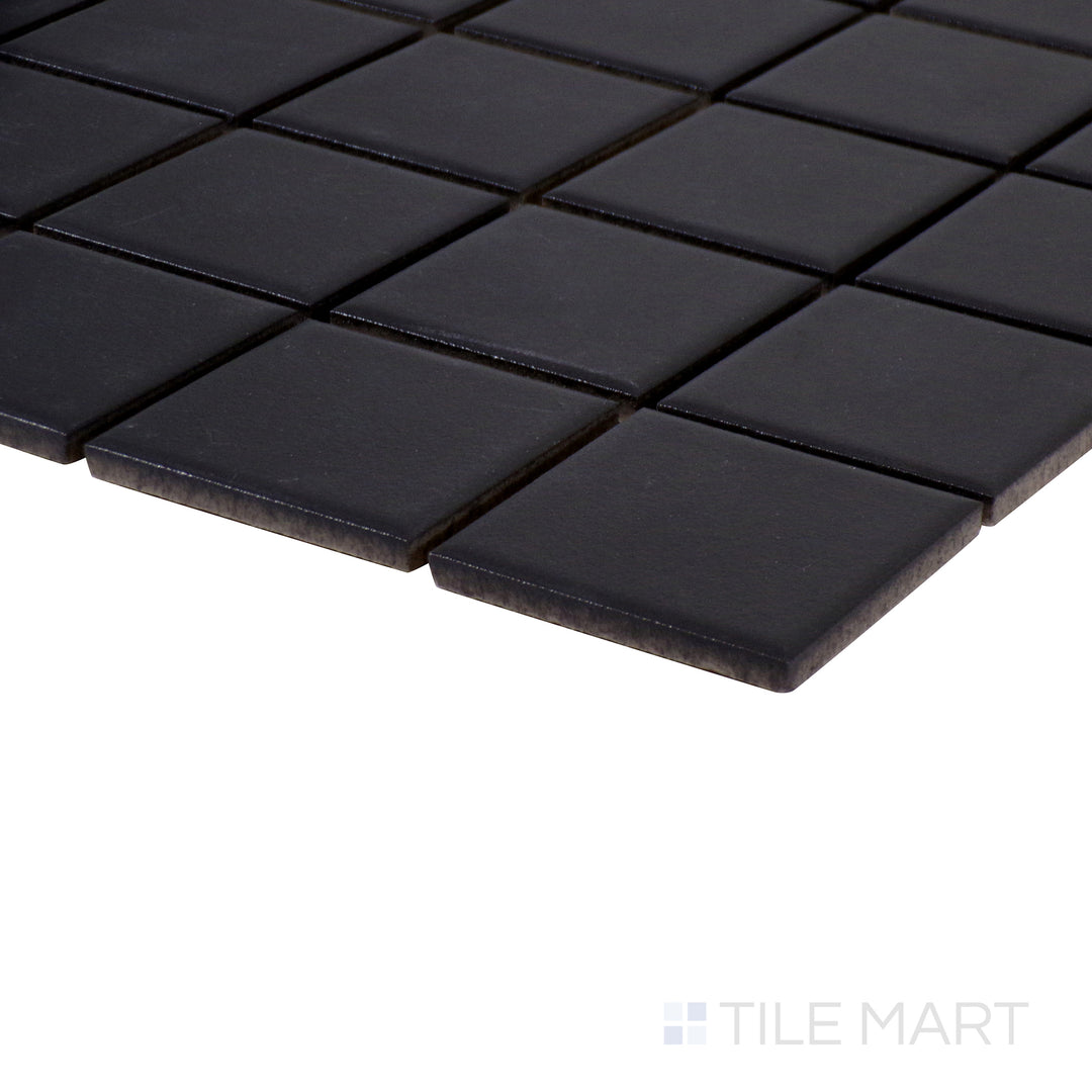 Angled close-up of Marin Black Sea 2" square matte glazed porcelain mosaic, featuring a bold black shade, non-reflective surface, and precisely aligned edge meeting.