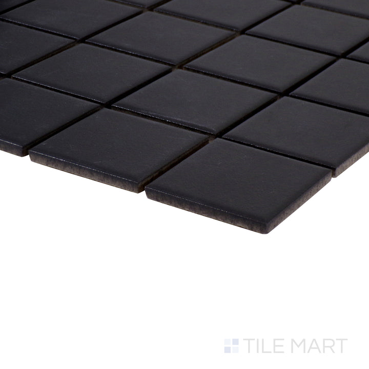 Angled close-up of Marin Black Sea 2" square matte glazed porcelain mosaic, featuring a bold black shade, non-reflective surface, and precisely aligned edge meeting.