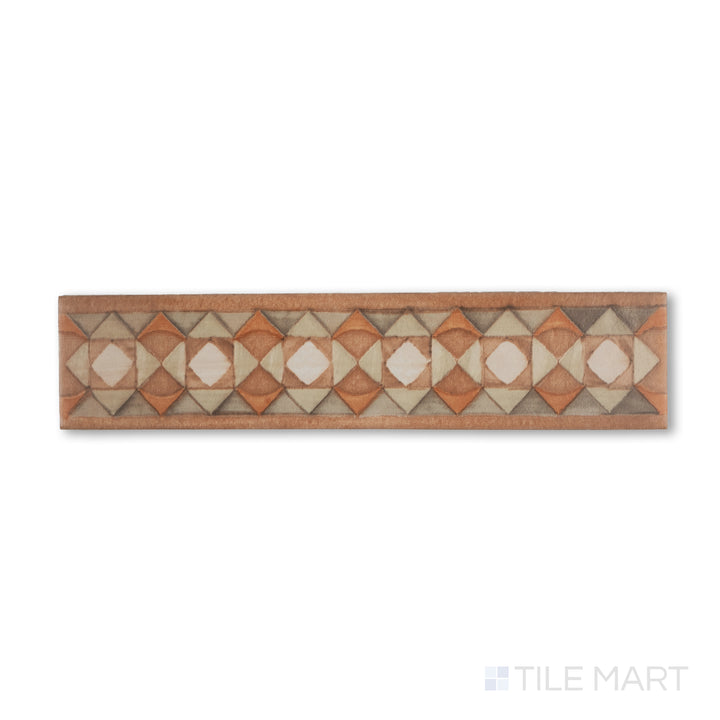 Flat-lay image of Cotto Nature Tira Volterra 3x14 gloss porcelain liner, showing an ornamental stripe pattern with hand-drawn appeal and warm, rustic coloration.