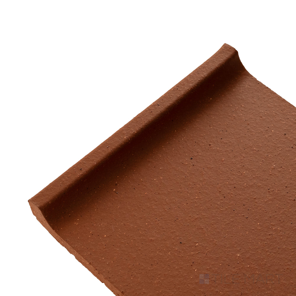 Corner detail of Metropolitan Mayflower Red 6x6 honed quarry cove base showing curved edge and smooth matte finish.