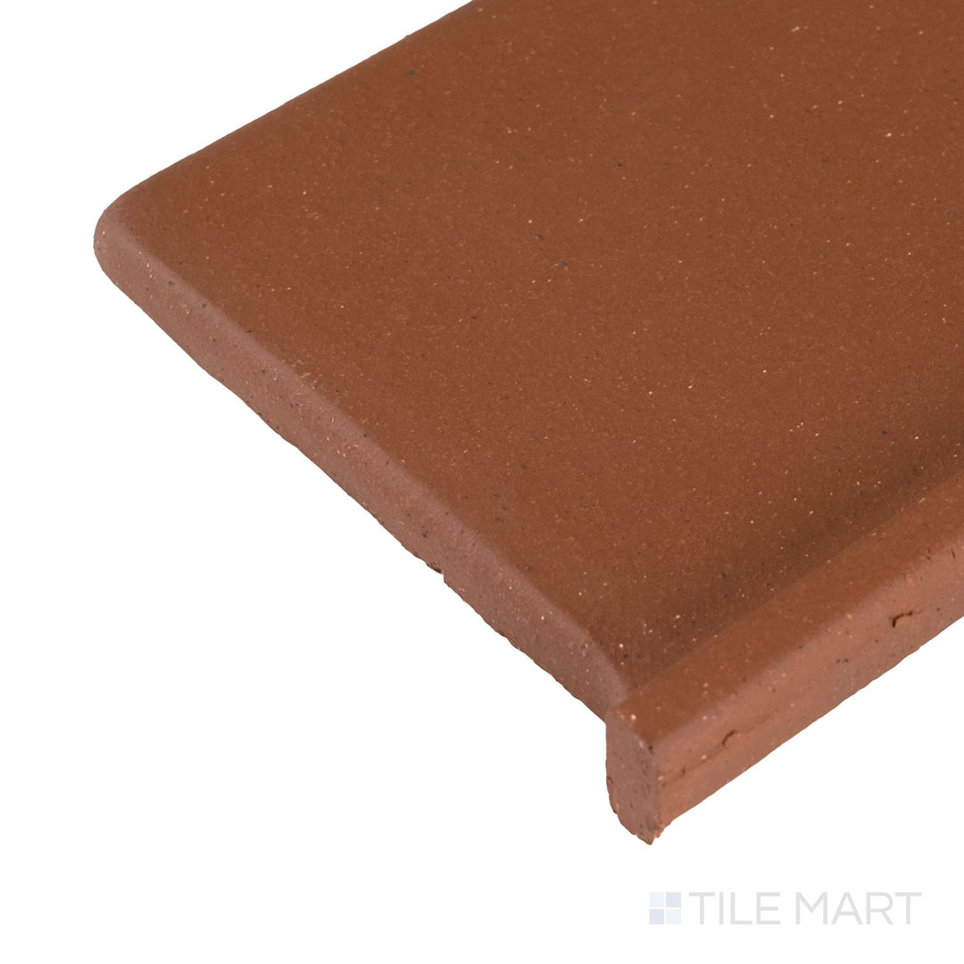 Corner close-up of Metropolitan Mayflower Red 6x6 honed quarry cove base right corner showing smooth curve and matte finish.