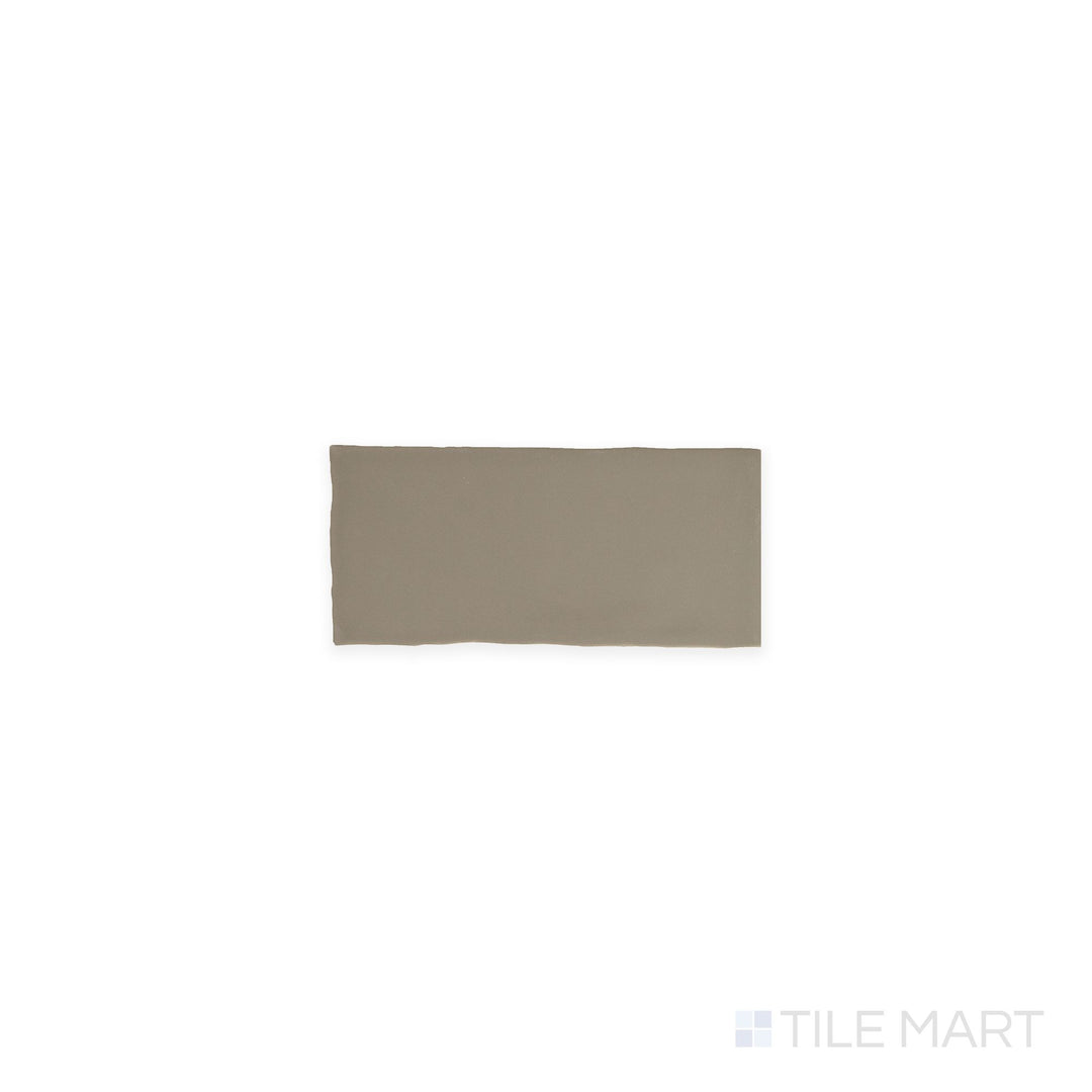 A top-down view of the Farrier Grullo 2.5x5 satin glazed ceramic tile displays a neutral taupe-gray color with a silky satin surface, offering subtle sophistication for walls and accents.
