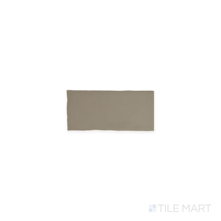 A top-down view of the Farrier Grullo 2.5x5 satin glazed ceramic tile displays a neutral taupe-gray color with a silky satin surface, offering subtle sophistication for walls and accents.