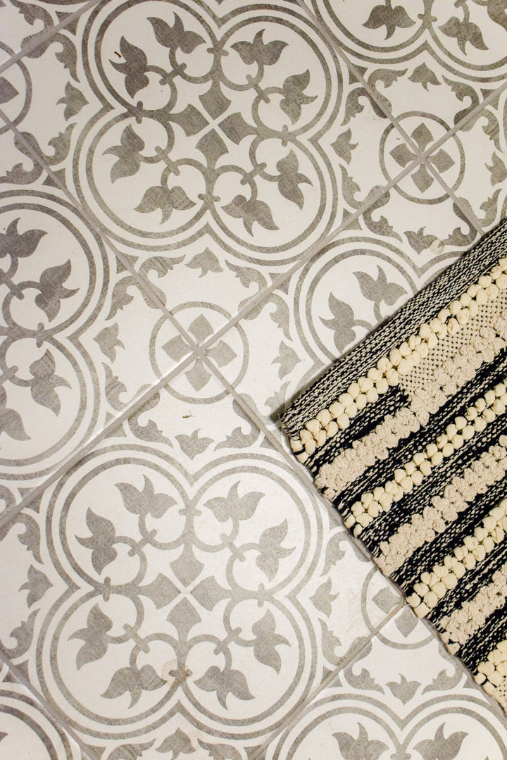 Installed in a finished room scene, the Memoir Petal Grey 12x12 matte glazed ceramic tile offers a calm neutral tone and timeless square format