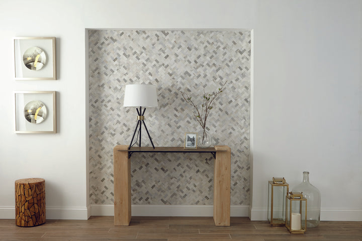 A refined blend of marble and limestone in a herringbone pattern creates a sophisticated and textured look in this mosaic tile.