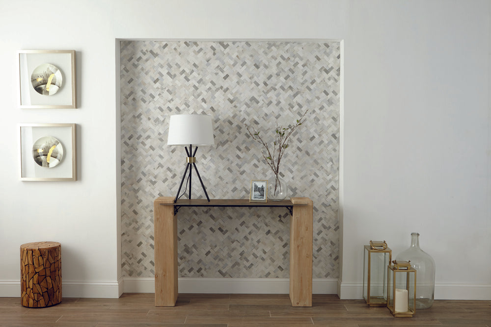 A refined blend of marble and limestone in a herringbone pattern creates a sophisticated and textured look in this mosaic tile.